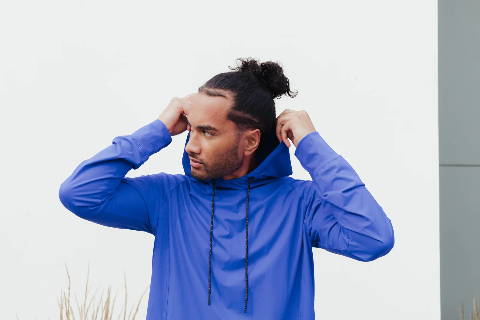 Model adjusting the hood of a vivid blue lightweight hoodie