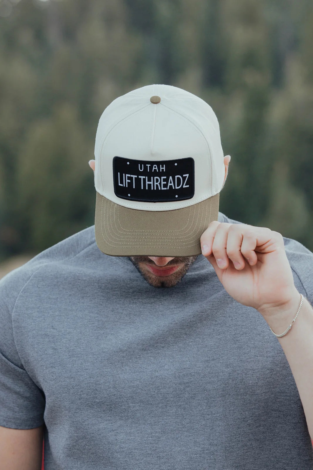 Close view of a Lift Threadz cap worn with a grey tee, showing its embroidered patch